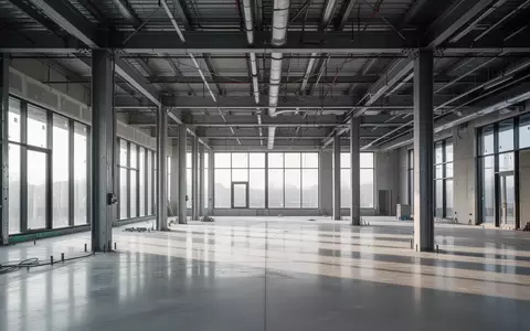 Moderne, minimalistische Innenansicht einer Baustelle mit Stahlträgern und Betonboden bei natürlichem Lichteinfall. - Foto: über boerse-global.de