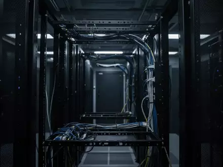 Dunkler, technischer Serverraum mit unbeschrifteten Kabelführungen in einem leeren Rack-Gestell. - Foto: über boerse-global.de