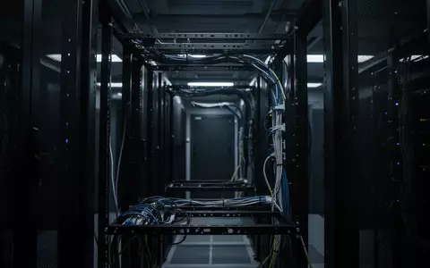 Dunkler, technischer Serverraum mit unbeschrifteten Kabelführungen in einem leeren Rack-Gestell. - Foto: über boerse-global.de