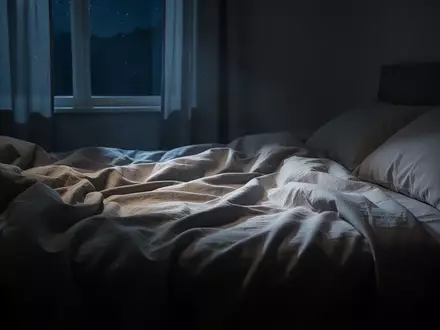 Ein ungemachtes Bett in einem ruhig beleuchteten Schlafzimmer während der Nacht, das eine Atmosphäre der Stille vermittelt. - Foto: über boerse-global.de