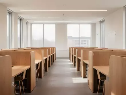 Leerer, moderner Lernraum in einer Bibliothek mit hölzernen Schreibtischen und hellem Tageslicht. - Foto: über boerse-global.de