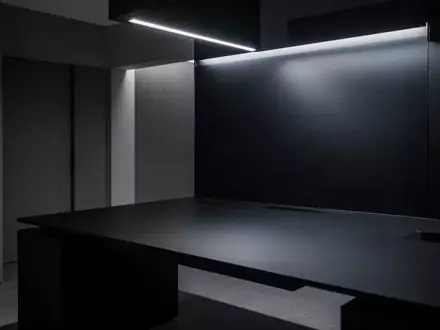 Ein minimalistischer, leerer Schreibtisch in einem modern beleuchteten Raum mit schlichten architektonischen Linien. - Foto: über boerse-global.de