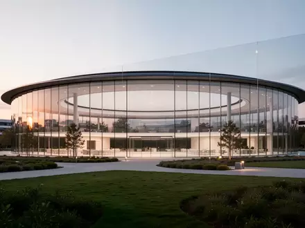 Die Architektur des Apple Park Gebäudes bei Dämmerung mit Fokus auf die Glasfassade und die umgebende Landschaft. - Foto: über boerse-global.de