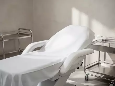 Ein minimalistisch eingerichteter, steriler Behandlungsraum in einer Klinik mit einer Liege und neutralen Wandtexturen. - Foto: über boerse-global.de