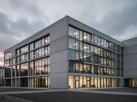 Ein modernes, minimalistisches Bürogebäude in Berlin bei bewölktem Dämmerlicht. - Foto: über boerse-global.de