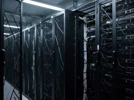 Ein minimalistischer, moderner Serverraum mit ordentlich angeordneten, unbeschrifteten Serverschränken in kühlem Licht. - Foto: über boerse-global.de