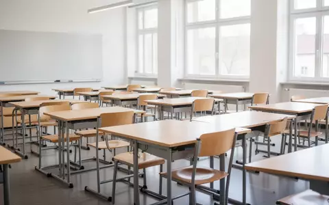 Ein heller, leerer Klassenraum in einer Schule mit ordentlich aufgereihten Holztischen und Stühlen bei Tageslicht. - Foto: über boerse-global.de
