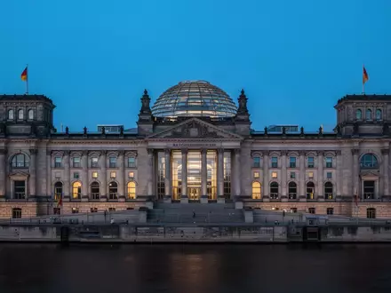 Das Berliner Reichstagsgebäude in der Abenddämmerung mit Blick auf die beleuchtete Glaskuppel. - Foto: über boerse-global.de