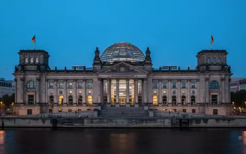 Das Berliner Reichstagsgebäude in der Abenddämmerung mit Blick auf die beleuchtete Glaskuppel. - Foto: über boerse-global.de