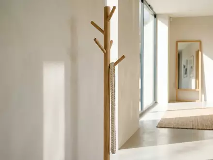 Eine schlichte Garderobe aus hellem Holz in einem lichtdurchfluteten Flur mit einer hängenden Textilkordel. - Foto: über boerse-global.de