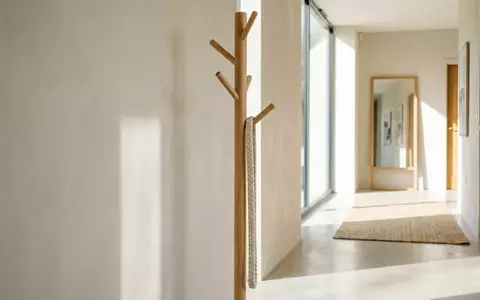 Eine schlichte Garderobe aus hellem Holz in einem lichtdurchfluteten Flur mit einer hängenden Textilkordel. - Foto: über boerse-global.de