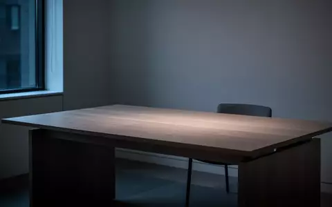 Ein minimalistischer, leerer Schreibtisch in einem abgedunkelten, modernen Raum mit sanftem, bläulichem Licht. - Foto: über boerse-global.de