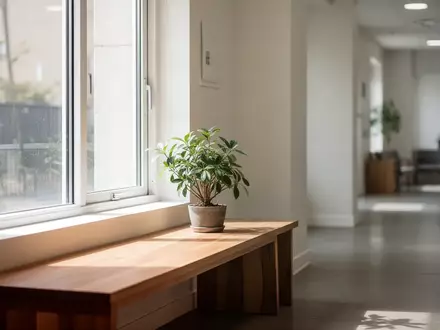 Ein heller, minimalistischer Wartebereich mit einem Holzsitzmöbel und einer Zimmerpflanze in einer ruhigen, freundlichen Umgebung. - Foto: über boerse-global.de
