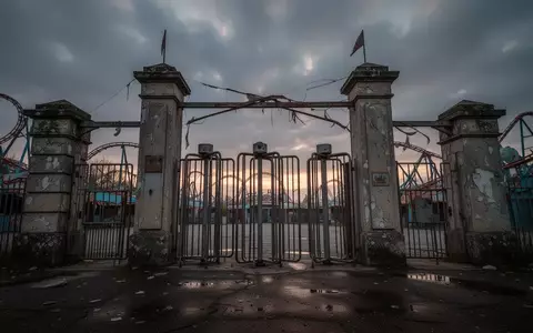 Leere Eingangstore eines Freizeitparks bei Dämmerung mit Drehkreuzen aus Eisen vor einem bewölkten Himmel. - Foto: über boerse-global.de