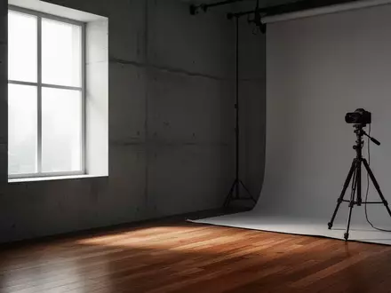 Ein minimalistisches Fotostudio mit neutralen Wänden, Holzboden und einem leeren Stativ in einem sanft beleuchteten Raum. - Foto: über boerse-global.de