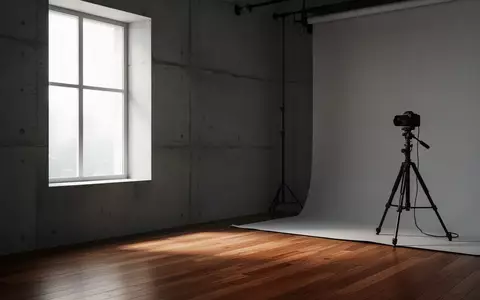 Ein minimalistisches Fotostudio mit neutralen Wänden, Holzboden und einem leeren Stativ in einem sanft beleuchteten Raum. - Foto: über boerse-global.de