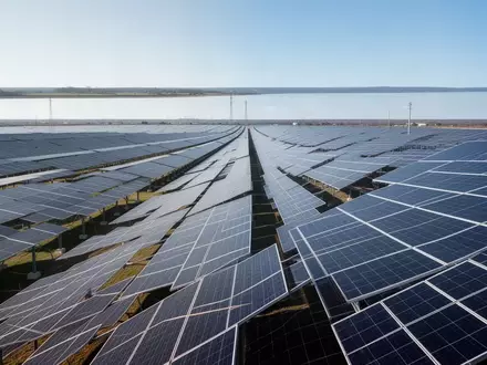 Weitläufige Solarparkanlage mit zahlreichen Photovoltaik-Modulen unter einem klaren Himmel. - Foto: über boerse-global.de