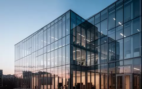Ein minimalistisches, modernes Bürogebäude aus Glas bei Dämmerung, das Transparenz und technologische Architektur symbolisiert. - Foto: über boerse-global.de