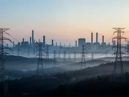 Hochspannungsmasten in einer südkoreanischen Industrielandschaft bei Dämmerung als Symbol für den steigenden Energiebedarf. - Foto: über boerse-global.de