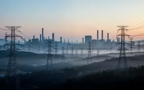 Hochspannungsmasten in einer südkoreanischen Industrielandschaft bei Dämmerung als Symbol für den steigenden Energiebedarf. - Foto: über boerse-global.de