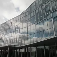 Moderne Glasfassade eines Verwaltungsgebäudes bei bewölktem Himmel. - Foto: über boerse-global.de