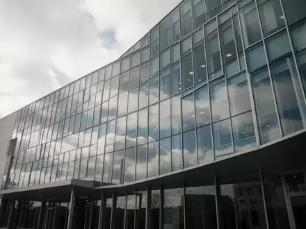 Moderne Glasfassade eines Verwaltungsgebäudes bei bewölktem Himmel. - Foto: über boerse-global.de