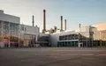 Weitwinkelaufnahme einer großen Industrieanlage bei Sonnenuntergang mit moderner Architektur und weitem Vorplatz. - Foto: über boerse-global.de