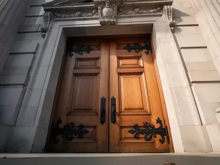 Schwere, kunstvolle Holztür eines Regierungsgebäudes in einer minimalistischen Architekturaufnahme. - Foto: über boerse-global.de