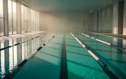 Ein helles, ruhiges Schwimmbecken in einer minimalistischen Architektur mit reflektierendem Wasser. - Foto: über boerse-global.de