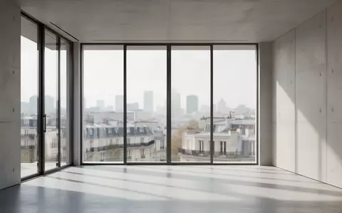 Ein minimalistisches, modernes Bürogebäude mit großen Glasfronten und Blick auf eine Stadtkulisse bei Tageslicht. - Foto: über boerse-global.de