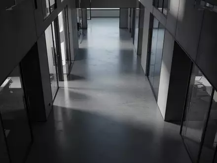 Ein leerer, modern gestalteter Büroflur mit polierten Betonböden und minimalistischer Architektur in natürlichem Licht. - Foto: über boerse-global.de