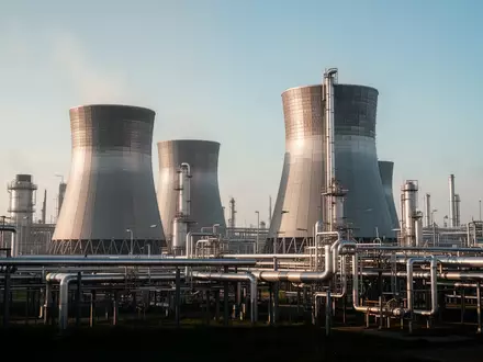 Industrielle Chemieanlage mit großen Kühltürmen und Rohrleitungssystemen vor klarem Himmel. - Foto: über boerse-global.de