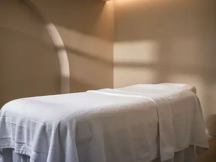 Ein minimalistischer, heller Behandlungsraum mit einer leeren, weiß bezogenen Liege in einer ruhigen Spa-Umgebung. - Foto: über boerse-global.de