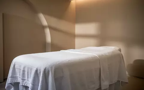 Ein minimalistischer, heller Behandlungsraum mit einer leeren, weiß bezogenen Liege in einer ruhigen Spa-Umgebung. - Foto: über boerse-global.de