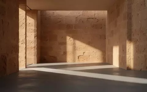 Ein minimalistischer, sonnendurchfluteter Innenraum mit strukturierten Steinwänden und klaren architektonischen Linien. - Foto: über boerse-global.de