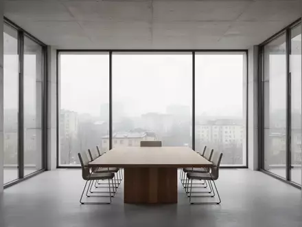Ein minimalistischer, leerer Konferenzraum mit großen Fenstern und Blick auf eine urbane Landschaft bei Tageslicht. - Foto: über boerse-global.de