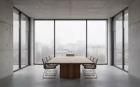 Ein minimalistischer, leerer Konferenzraum mit großen Fenstern und Blick auf eine urbane Landschaft bei Tageslicht. - Foto: über boerse-global.de