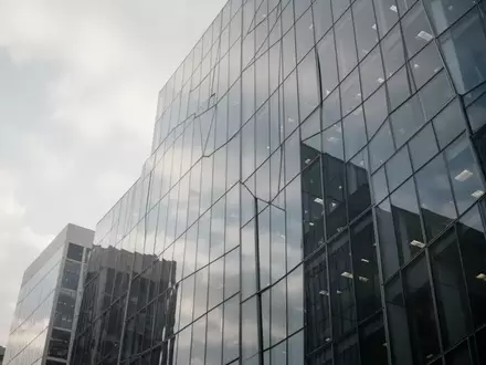 Moderne Glasfassade eines Bürogebäudes bei bewölktem Himmel als Symbol für Finanzpolitik und Steuergesetzgebung. - Foto: über boerse-global.de
