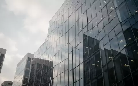 Moderne Glasfassade eines Bürogebäudes bei bewölktem Himmel als Symbol für Finanzpolitik und Steuergesetzgebung. - Foto: über boerse-global.de