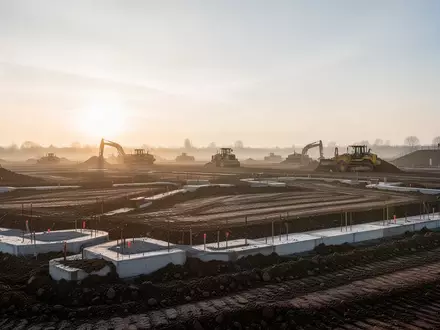Eine Baustelle in der Morgendämmerung mit Erdarbeiten auf einer weiten Fläche. - Foto: über boerse-global.de