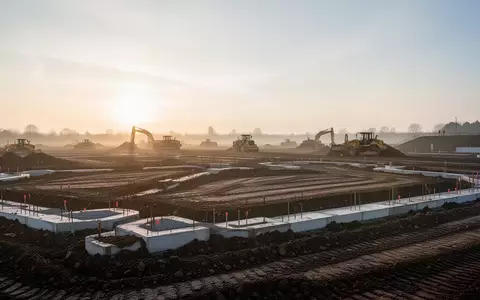 Eine Baustelle in der Morgendämmerung mit Erdarbeiten auf einer weiten Fläche. - Foto: über boerse-global.de