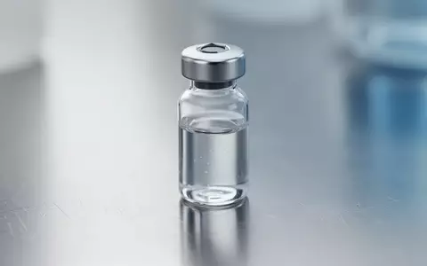 Ein steriles Laborglasfläschchen mit klarer Flüssigkeit auf einer Metalloberfläche in einer klinischen Laborumgebung. - Foto: über boerse-global.de