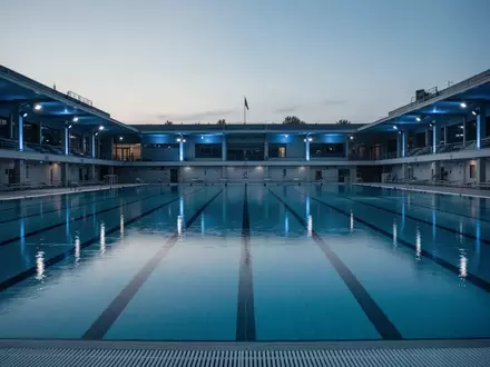 Ein leeres olympisches Schwimmbecken in der Abenddämmerung mit ruhigem Wasser und sanfter Beleuchtung. - Foto: über boerse-global.de