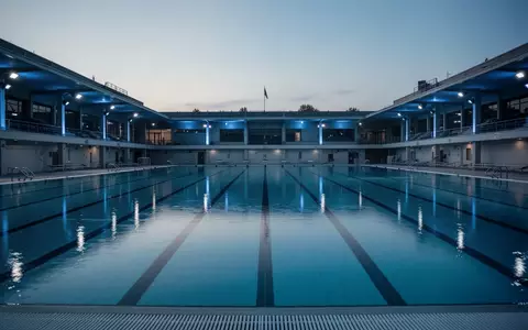 Ein leeres olympisches Schwimmbecken in der Abenddämmerung mit ruhigem Wasser und sanfter Beleuchtung. - Foto: über boerse-global.de