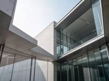 Moderne Architektur mit klaren Linien aus Beton und Glas bei hellem Tageslicht. - Foto: über boerse-global.de