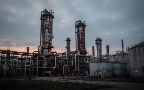 Eine weitläufige Industrieanlage mit stählernen Destillationstürmen und Rohrleitungen vor einem bewölkten Abendhimmel. - Foto: über boerse-global.de