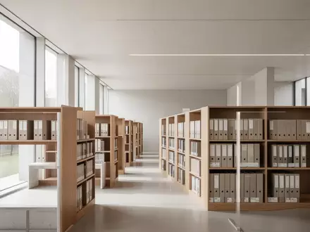 Minimalistisch gestalteter Bibliotheksraum mit hellen Holzregalen und einfallendem Tageslicht. - Foto: über boerse-global.de