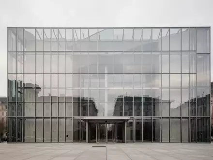 Moderne Glas- und Stahlfassade eines Regierungsgebäudes vor einem bewölkten Himmel. - Foto: über boerse-global.de