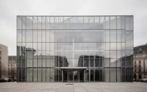 Moderne Glas- und Stahlfassade eines Regierungsgebäudes vor einem bewölkten Himmel. - Foto: über boerse-global.de