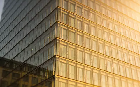 Ein modernes Bürogebäude mit Glasfassade bei Sonnenuntergang als Symbol für Immobilienentwicklung. - Foto: über boerse-global.de